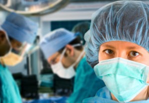 Surgeons in an operating room, with one of them looking at the camera