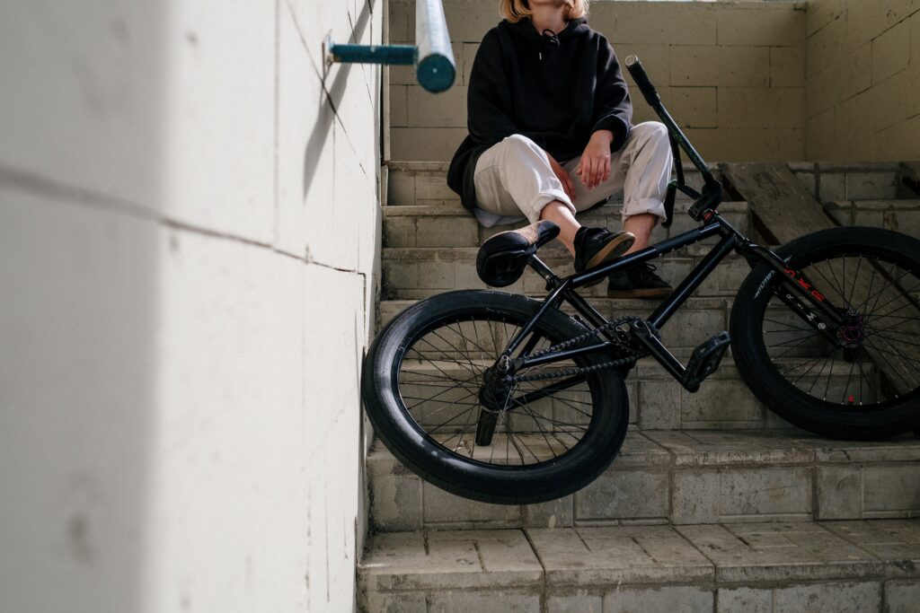 Person sitting in a stairwell with their bicycle