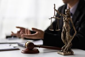 A lawyer is going over legal documents. There are items on the desk, such as a figure of Lady Justice and a gavel.